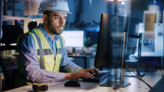 Man in a hard hat working on a computer